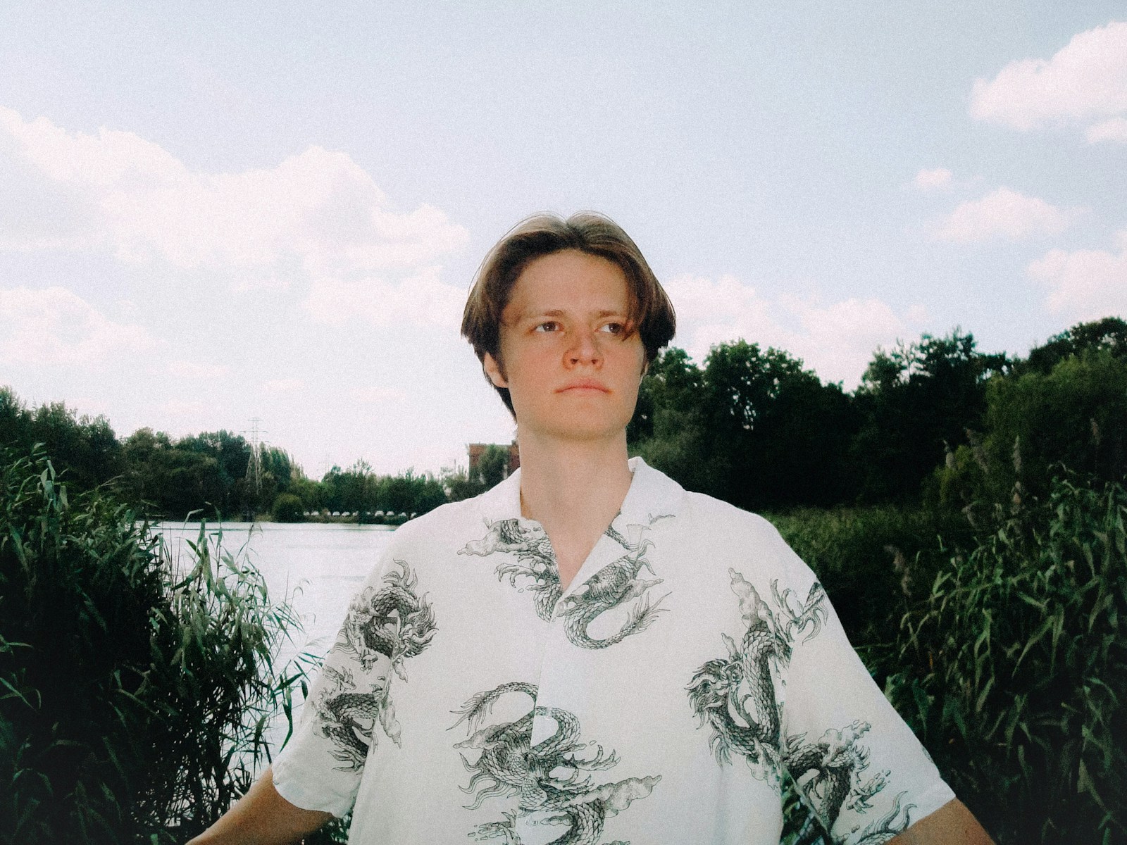 Young man in patterned shirt by a lake